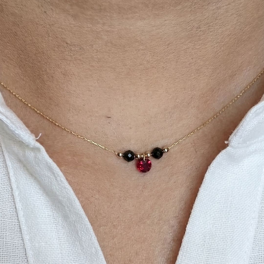 Necklace with red and black beads worn by a person with a white shirt