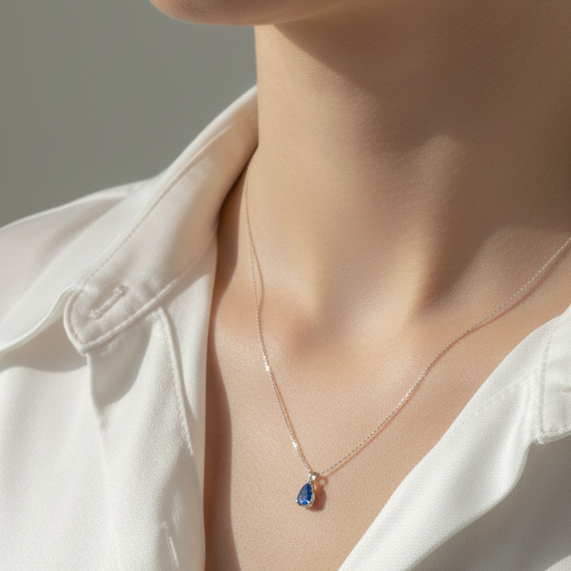 Close-up of a person wearing a delicate 925 sterling silver necklace featuring a blue zircon pendant.