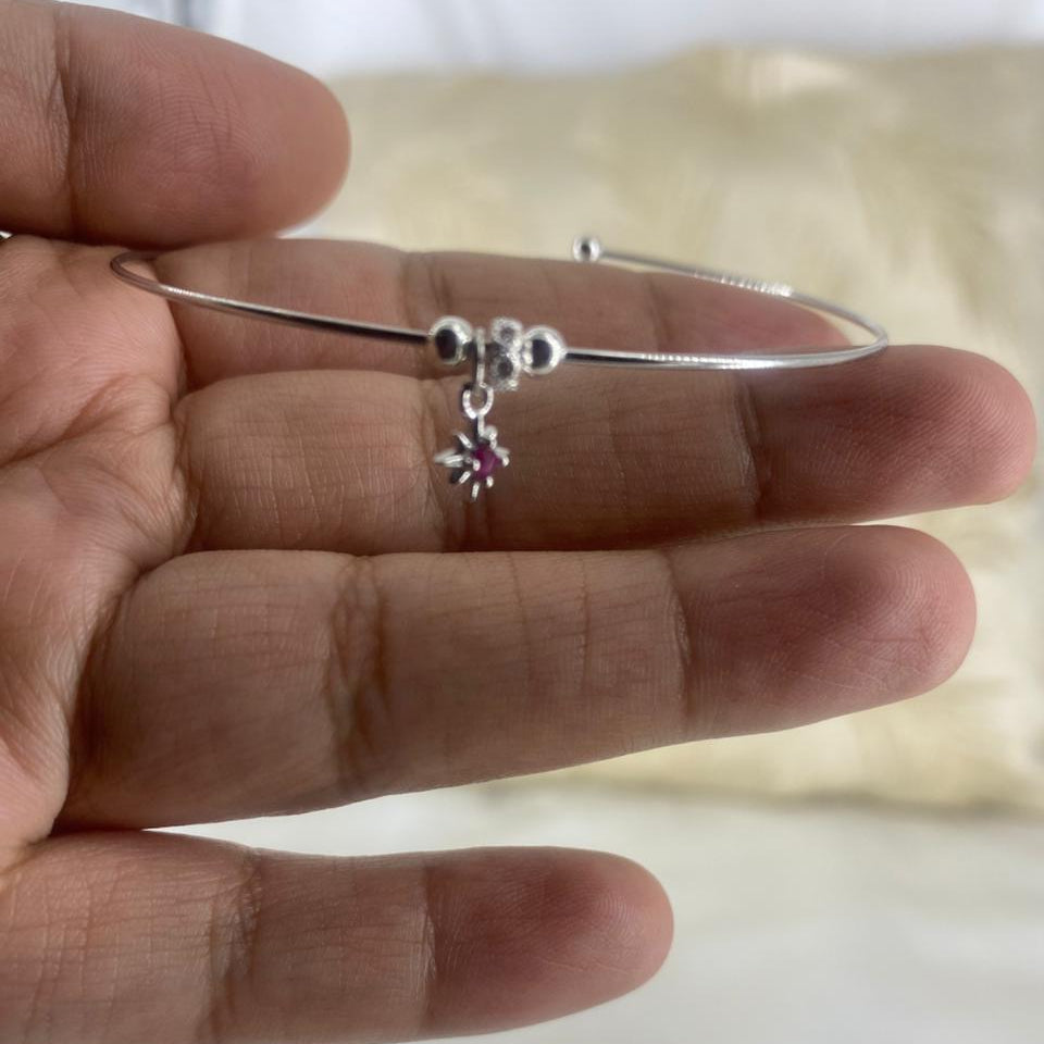 Silver bracelet with a star-shaped charm on a hand against a neutral background