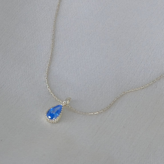 Silver necklace with a blue teardrop pendant