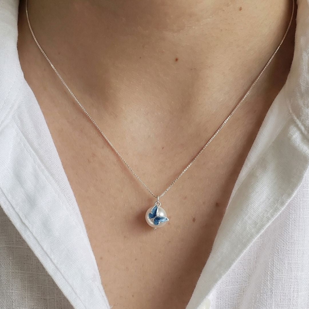 Necklace with a blue heart pendant worn by a person in a white shirt, with 'MinniM' branding.