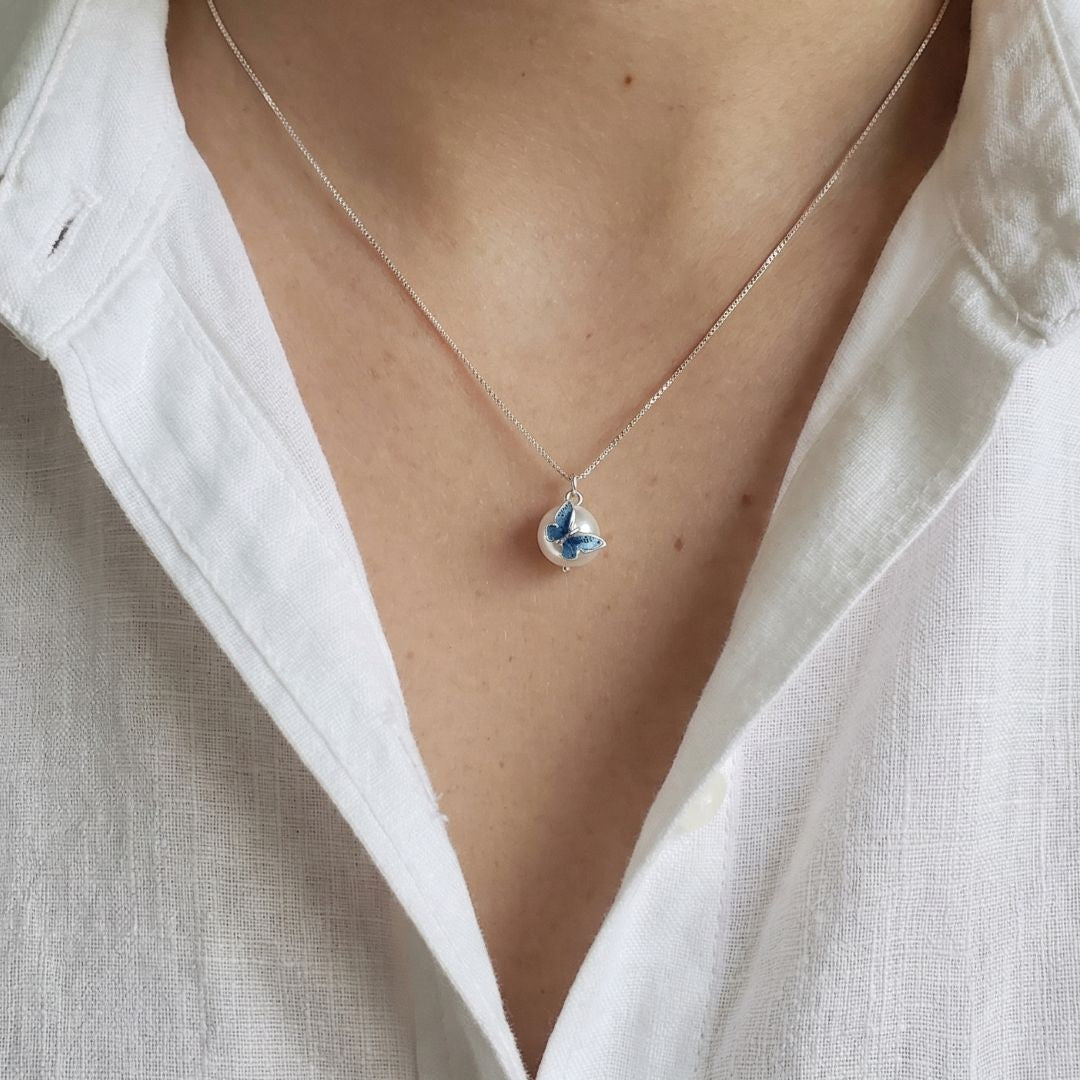 Necklace with a blue pendant worn by a person in a white shirt, with 'Minnim' branding.