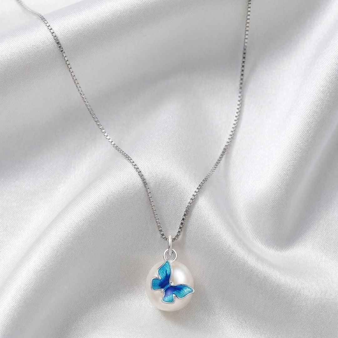 Necklace with a blue butterfly pendant on a white satin background, featuring the brand 'MinniM'.