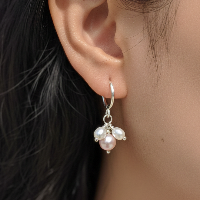 Close-up of an ear wearing a pearl earring with blurred hair and background