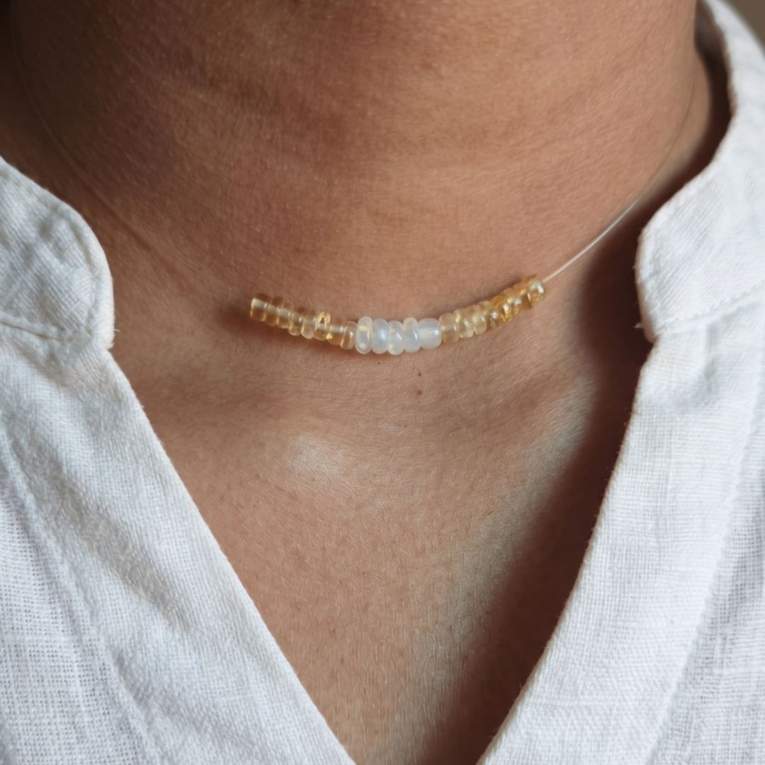 Necklace with small beads worn by a person in a white shirt