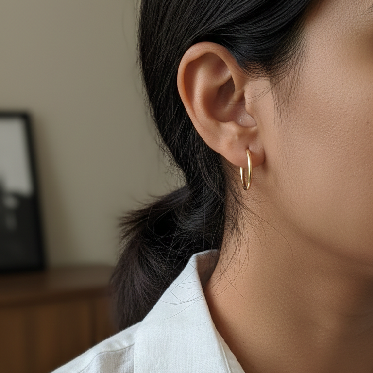 Close-up of a person wearing a gold hoop earring with a blurred background