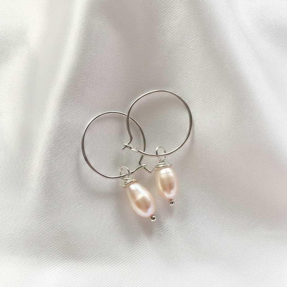 Pair of hoop earrings with pearl drops on a light fabric background
