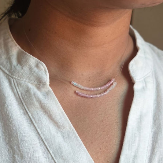Person wearing a delicate necklace with a plain background